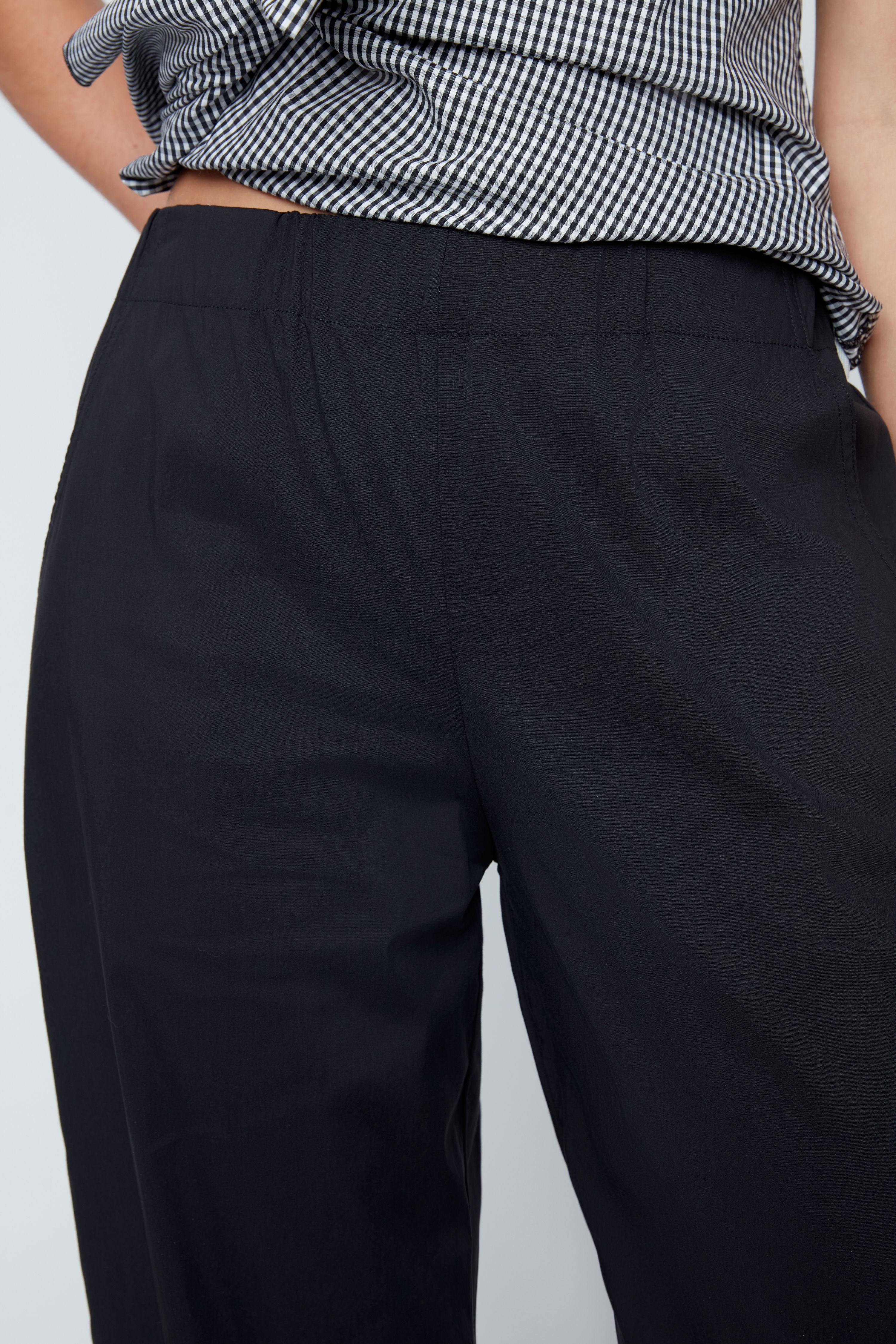 Black pants worn by a person on a light gray background
