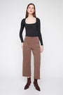 Woman wearing a black long-sleeve top and brown pants on a white background
