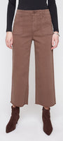 A model wearing brown wide-leg cropped pants with a black long-sleeve top and dark brown pointed-toe ankle boots, shown from the waist down against a light gray studio background.