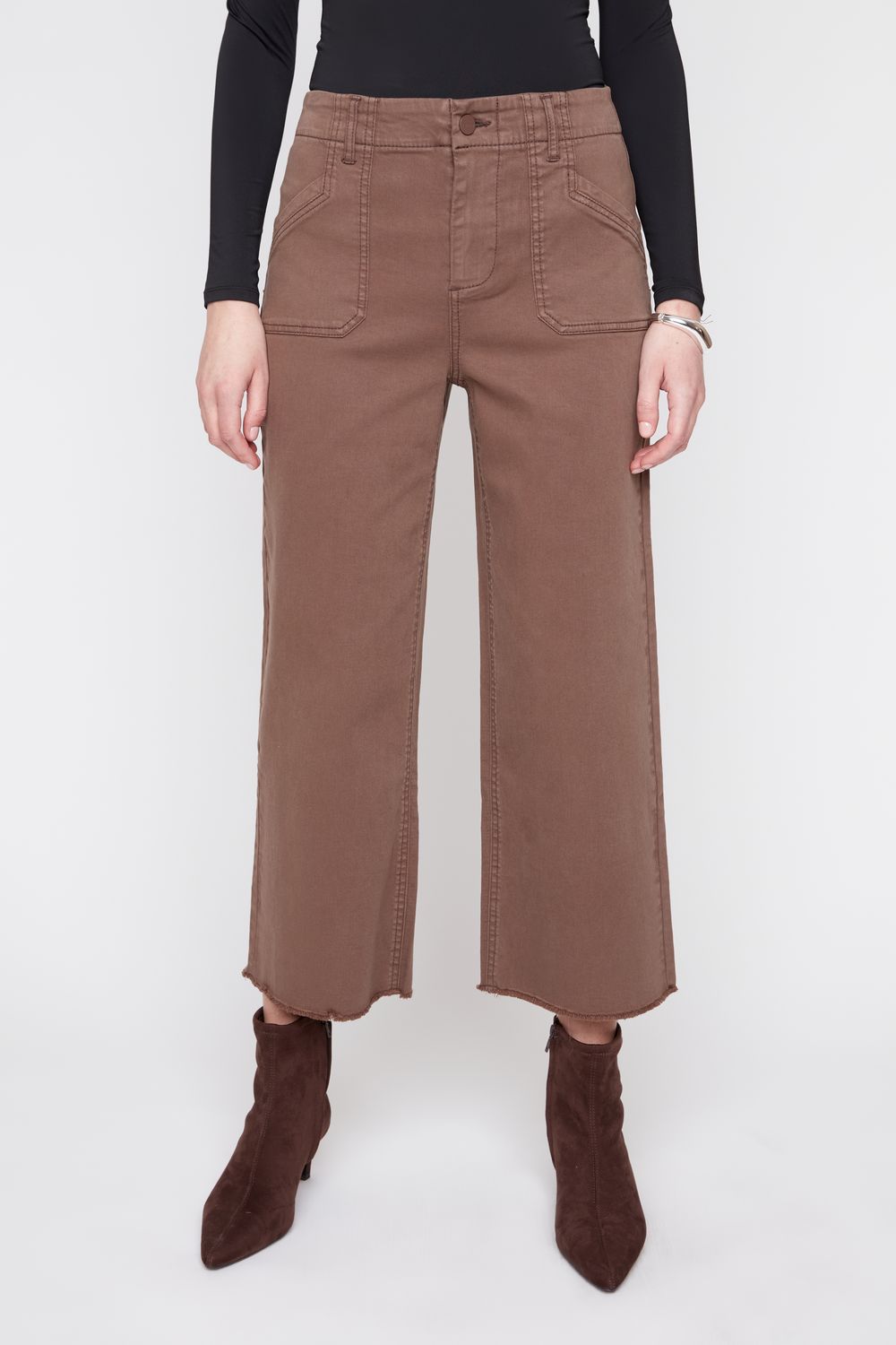 A model wearing brown wide-leg cropped pants with a black long-sleeve top and dark brown pointed-toe ankle boots, shown from the waist down against a light gray studio background.