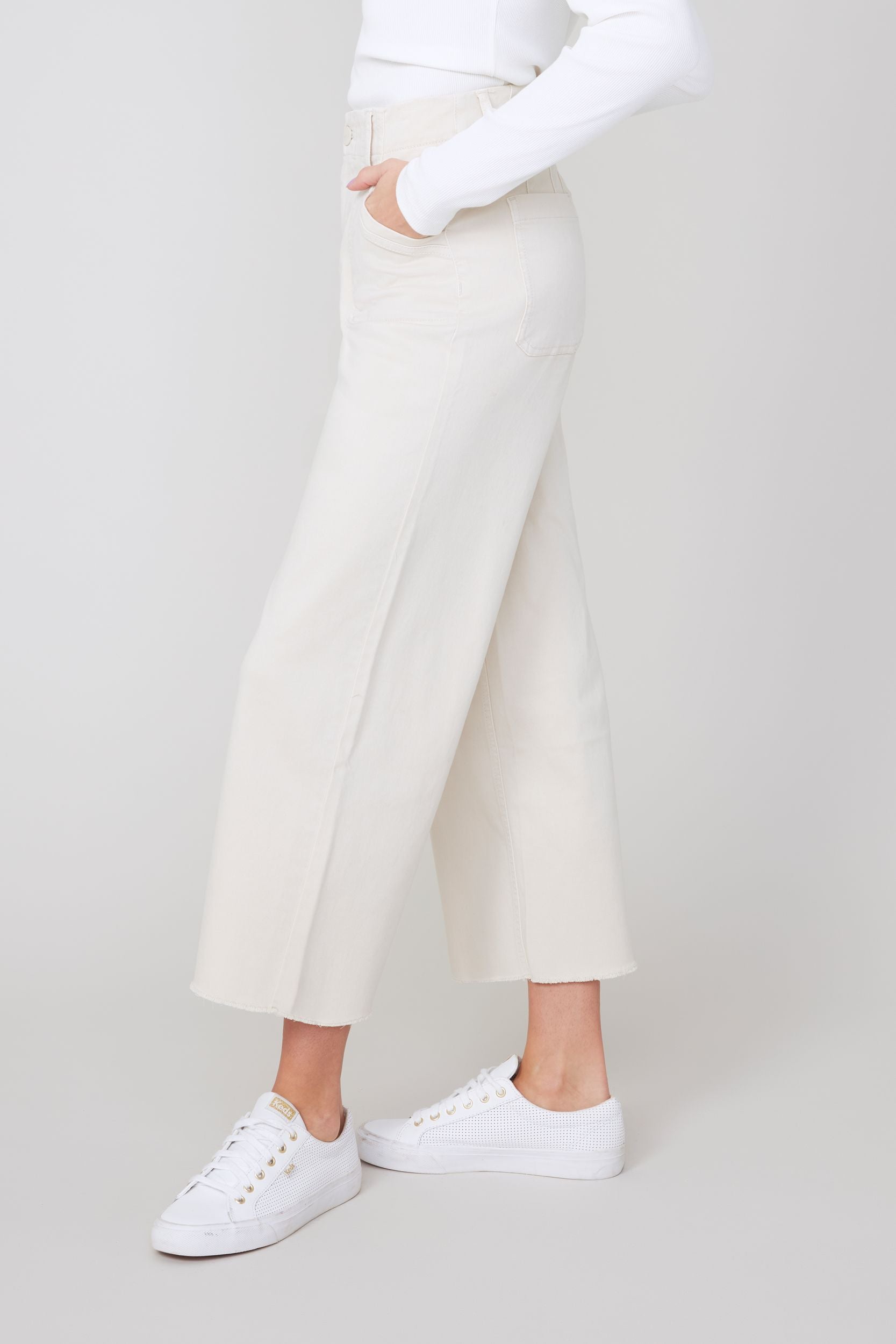 Person wearing oyster colored pants and sneakers on a plain background