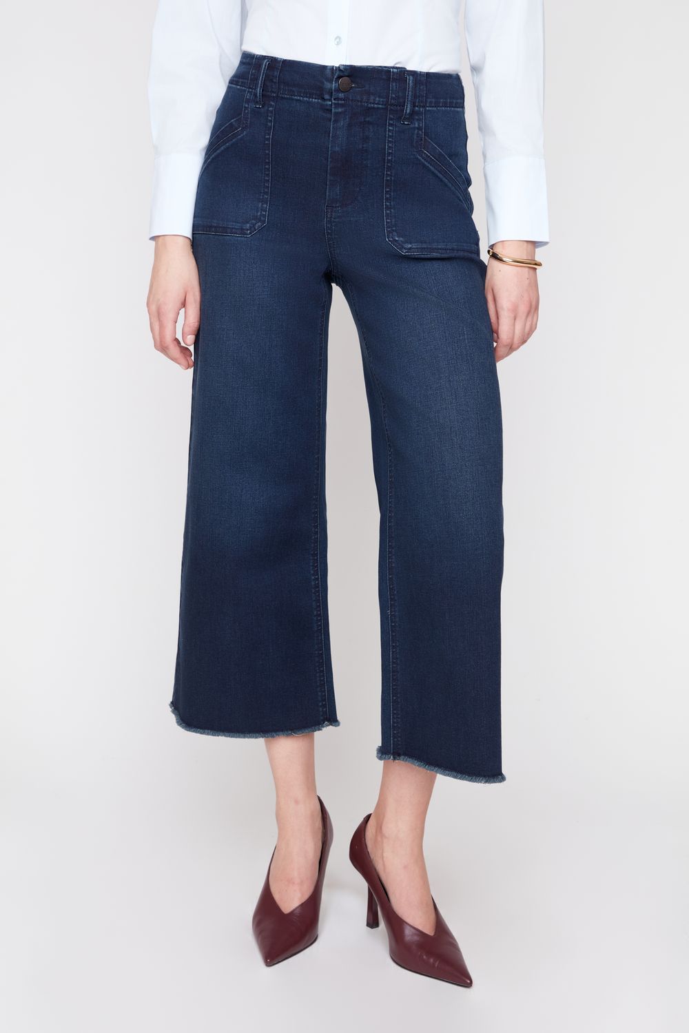 Person wearing dark blue jeans and brown shoes on a white background