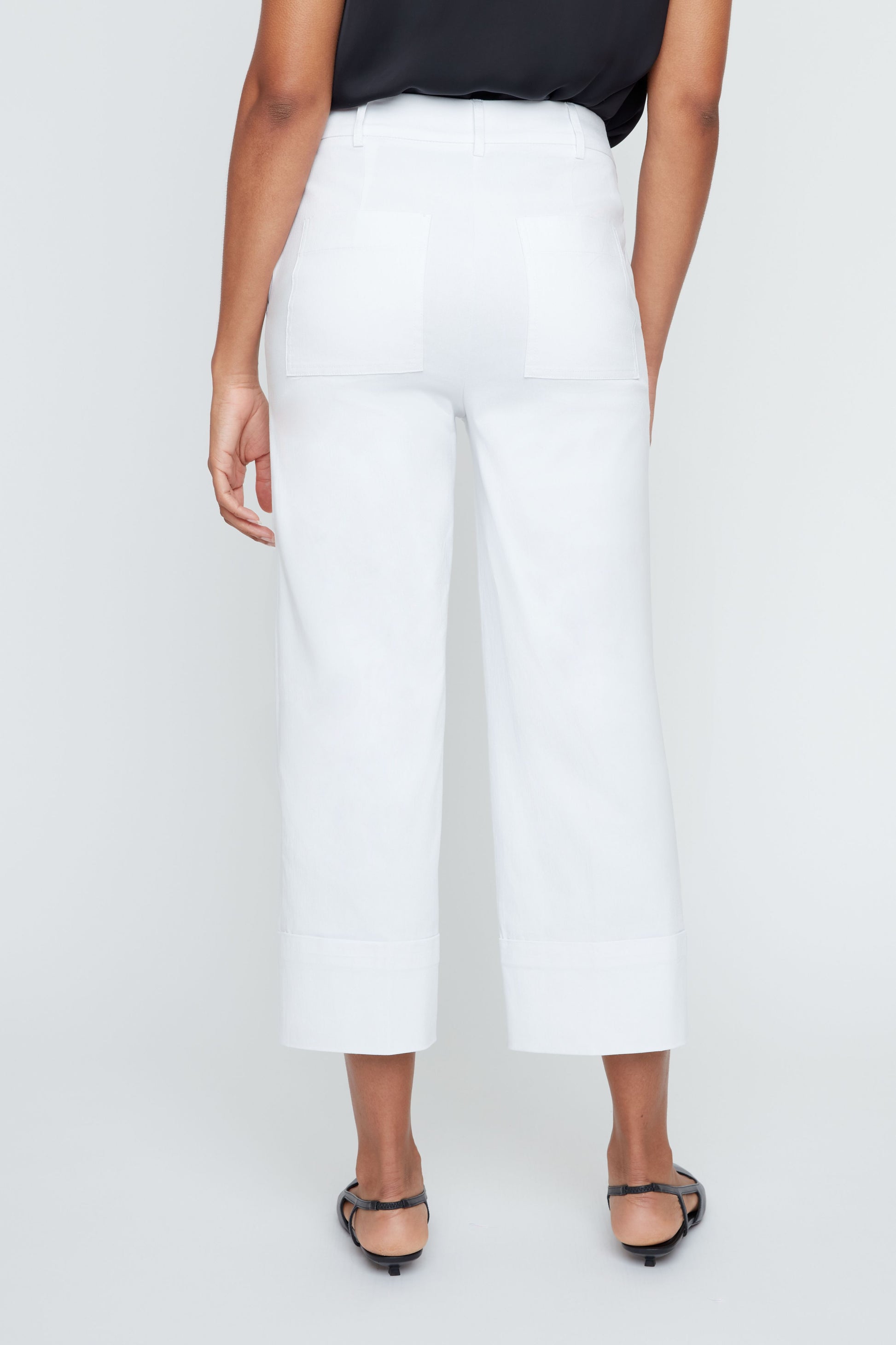 Person wearing white pants on a plain background