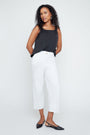 Woman wearing a black sleeveless top and white pants on a white background
