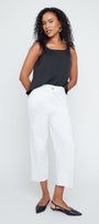 Woman wearing a black sleeveless top and white pants on a white background