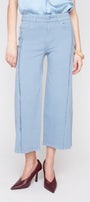 A model wearing light blue cropped wide-leg pants, a light blue satin top, and dark burgundy pointed-toe heels, shown from the waist down against a light gray studio background.