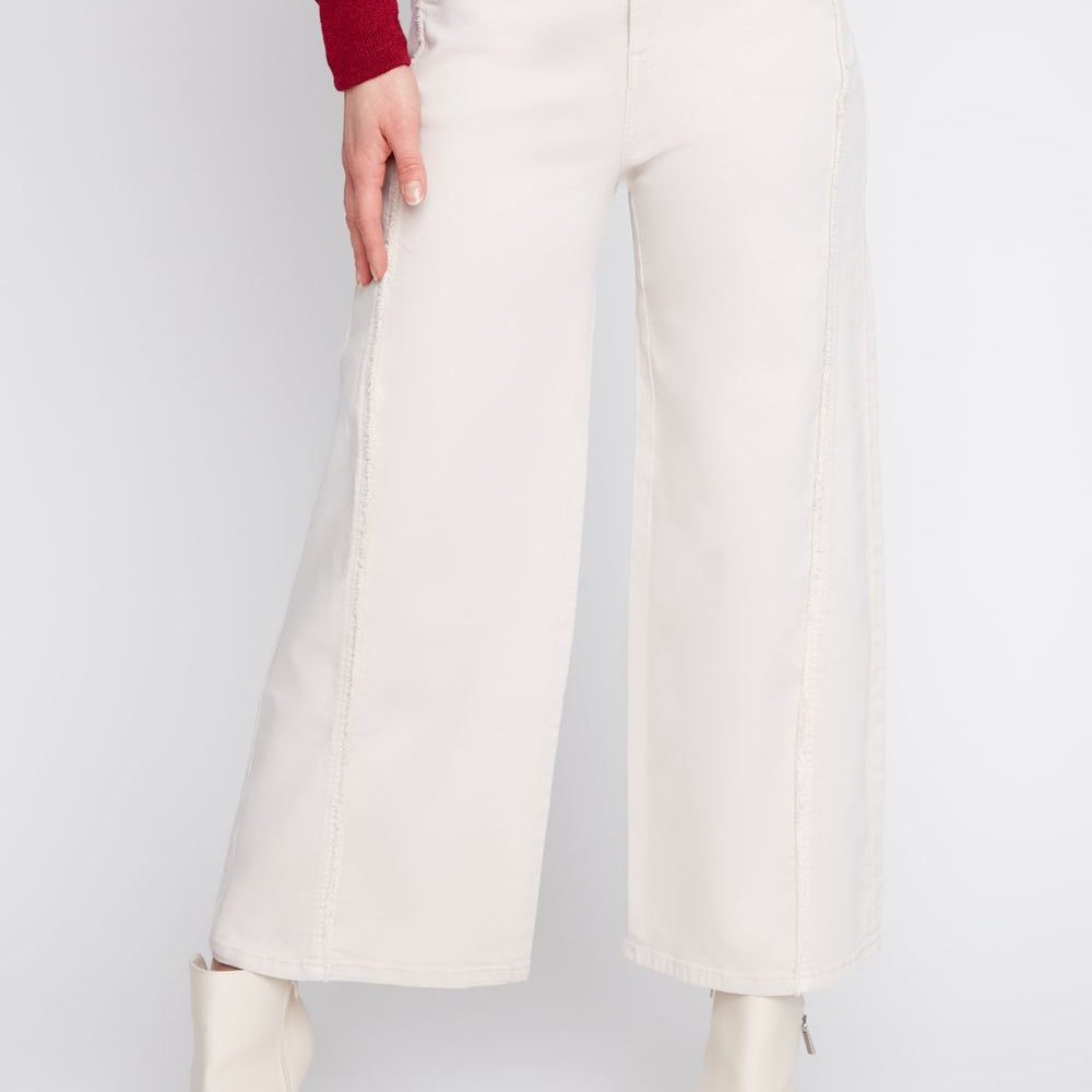 Person wearing white wide-leg pants and white boots on a plain background