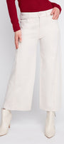 Person wearing white wide-leg pants and white boots on a plain background