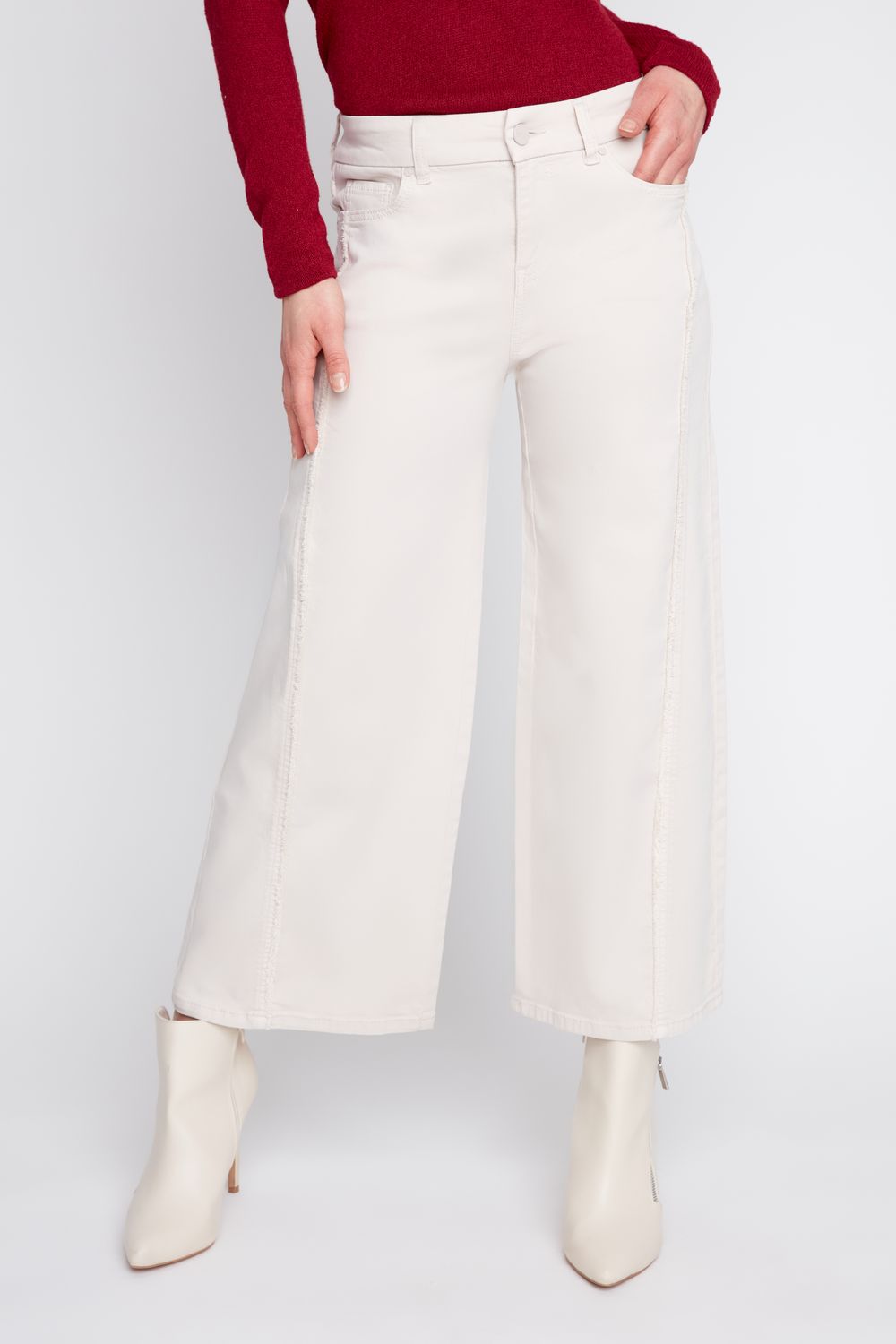 Person wearing white wide-leg pants and white boots on a plain background