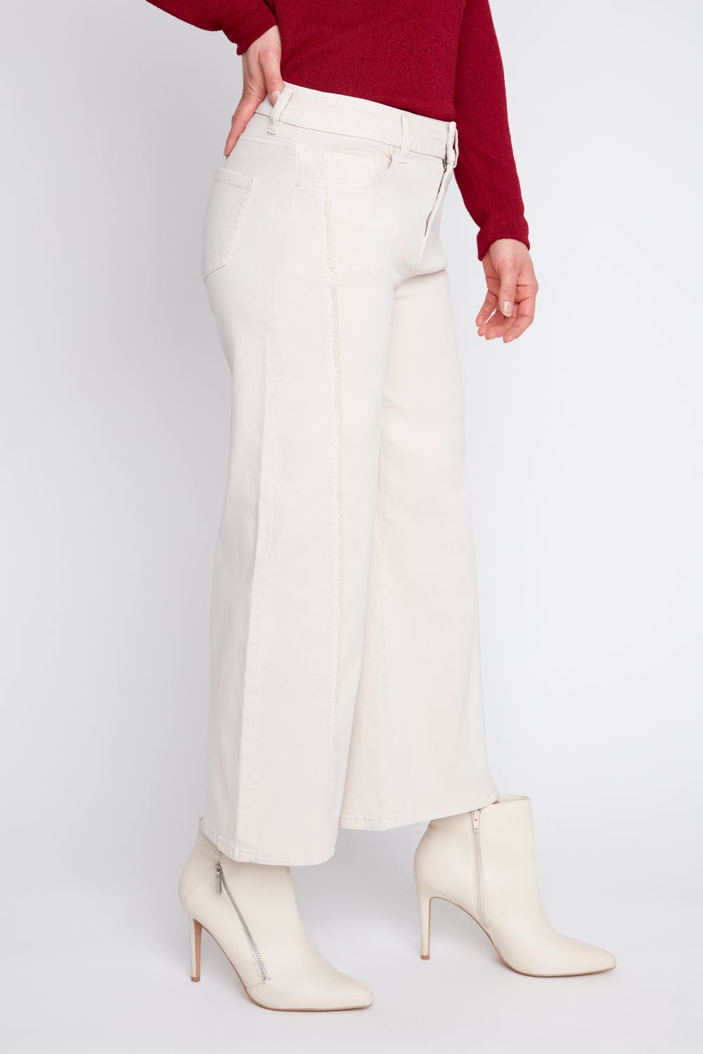 A model wearing off-white wide-leg cropped pants, a dark red long-sleeve top, and off-white pointed-toe ankle boots with high stiletto heels, shown from the waist down on a light gray studio background.
