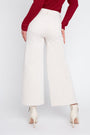 Person wearing white wide-leg pants with a red top on a white background