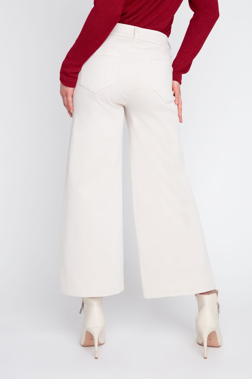 Person wearing white wide-leg pants with a red top on a white background