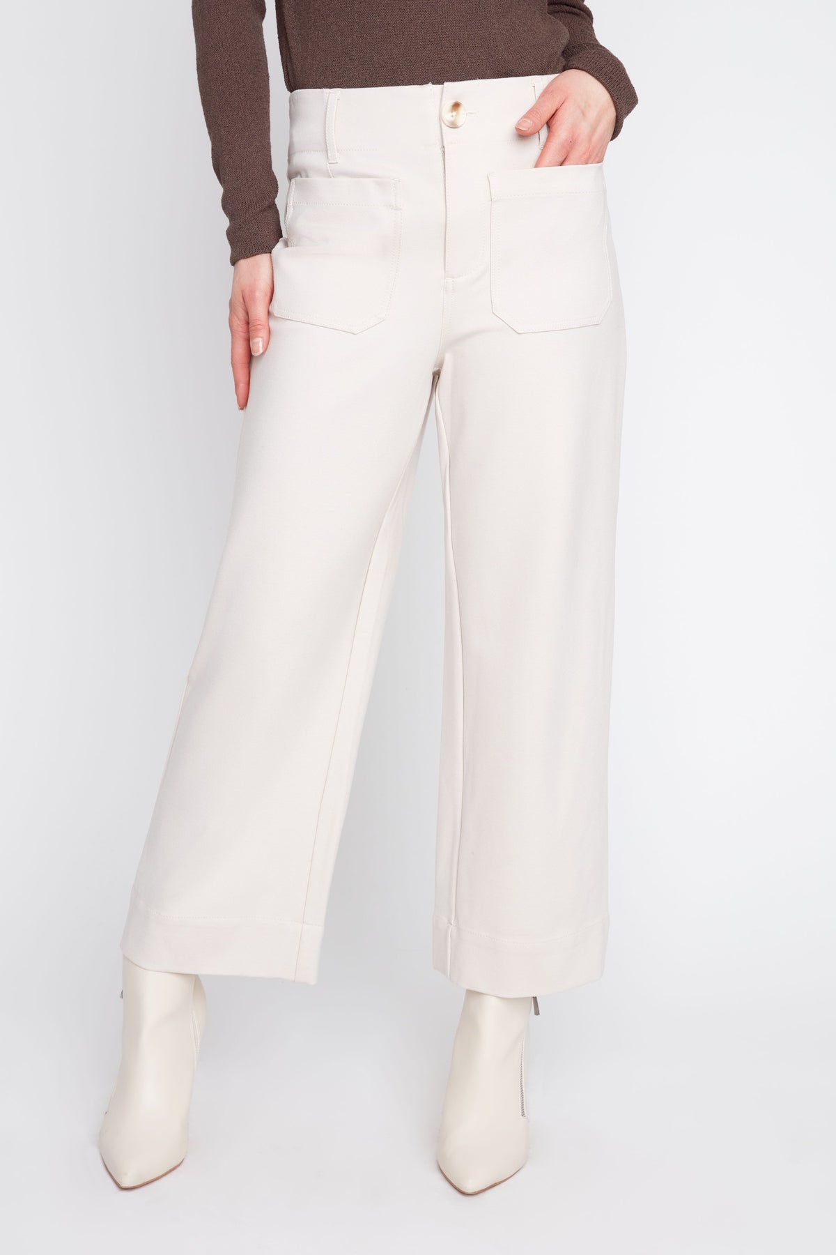 Person wearing white pants and white boots on a light gray background