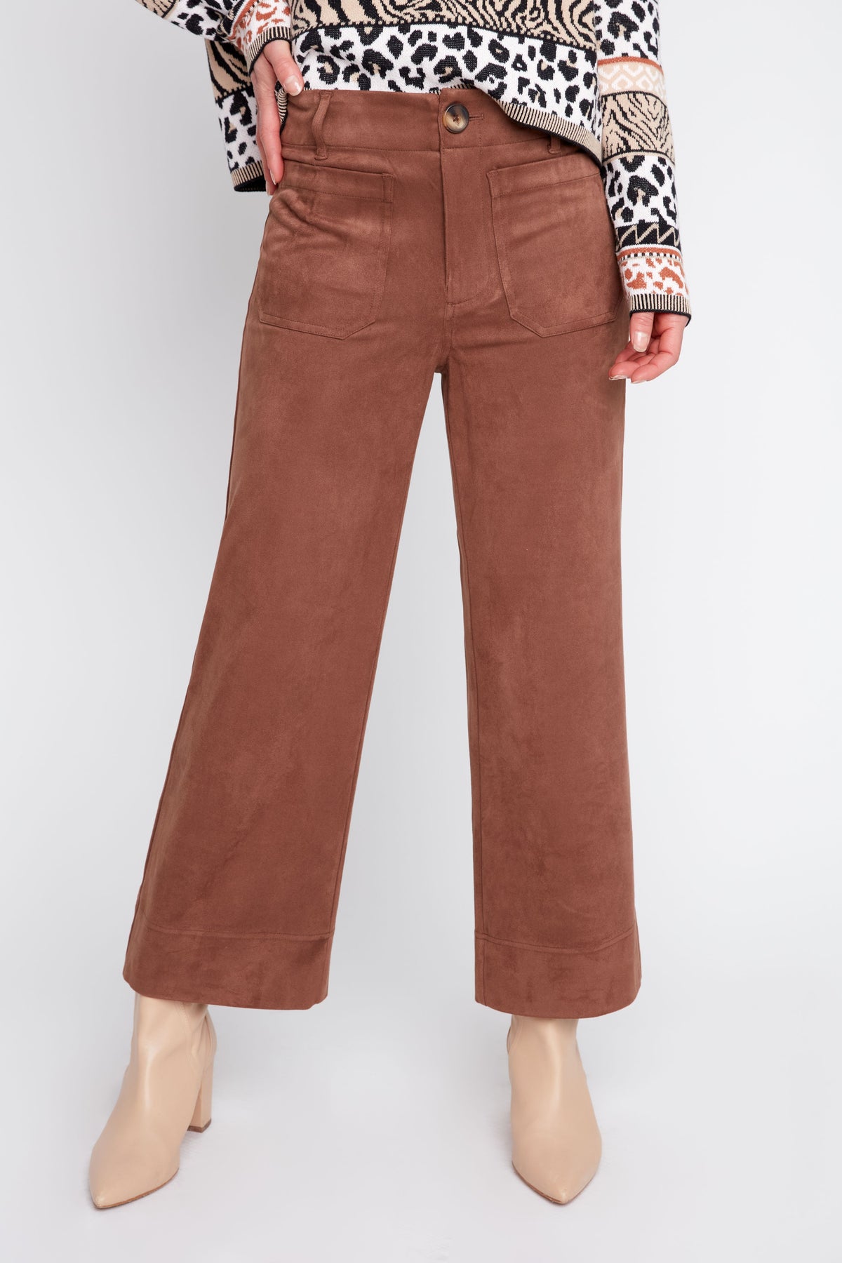 Brown corduroy pants worn by a person on a white background