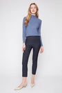 Woman wearing a blue long-sleeve top and black pants on a white background
