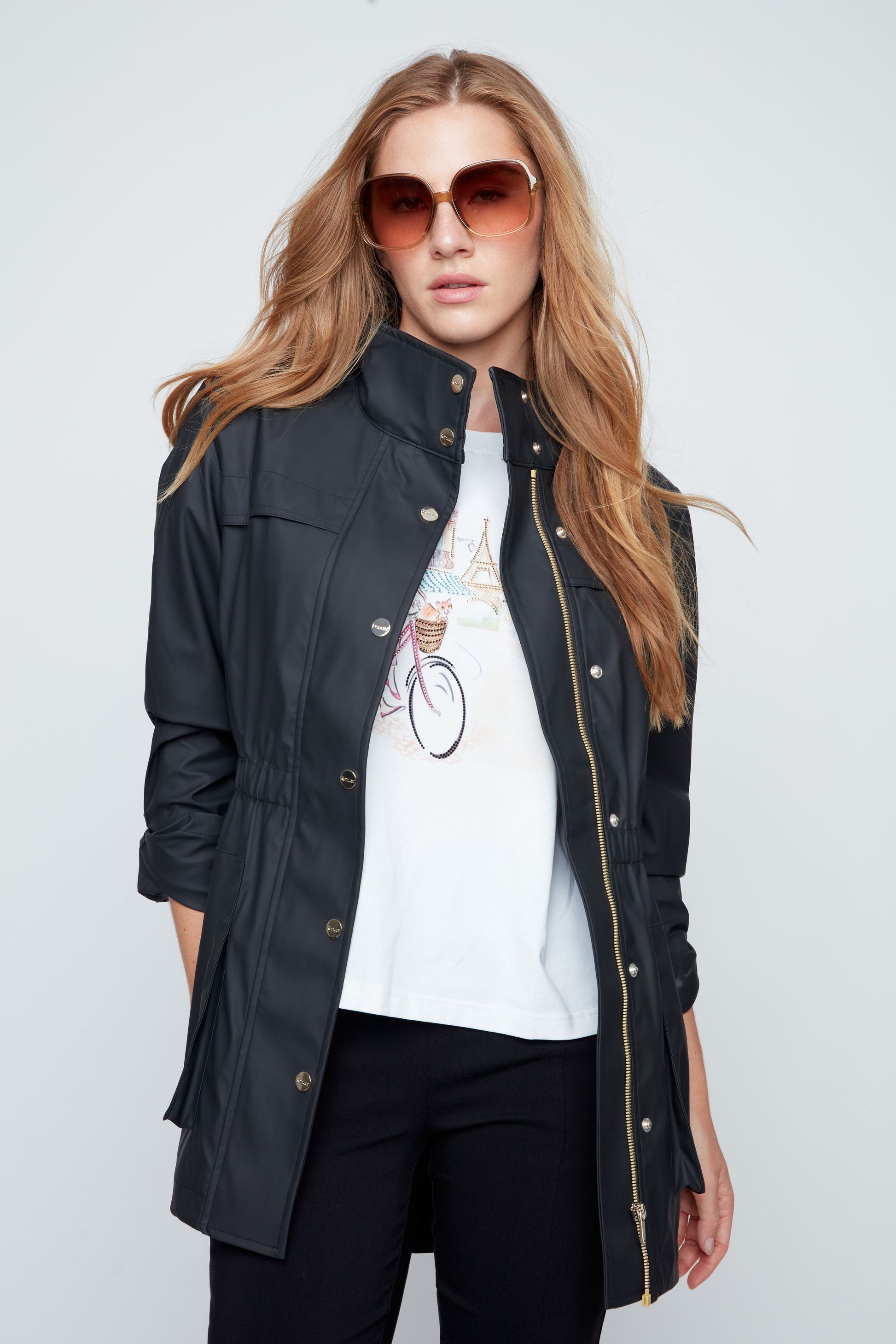 Woman wearing a black jacket over a white t-shirt with a graphic design on a plain background