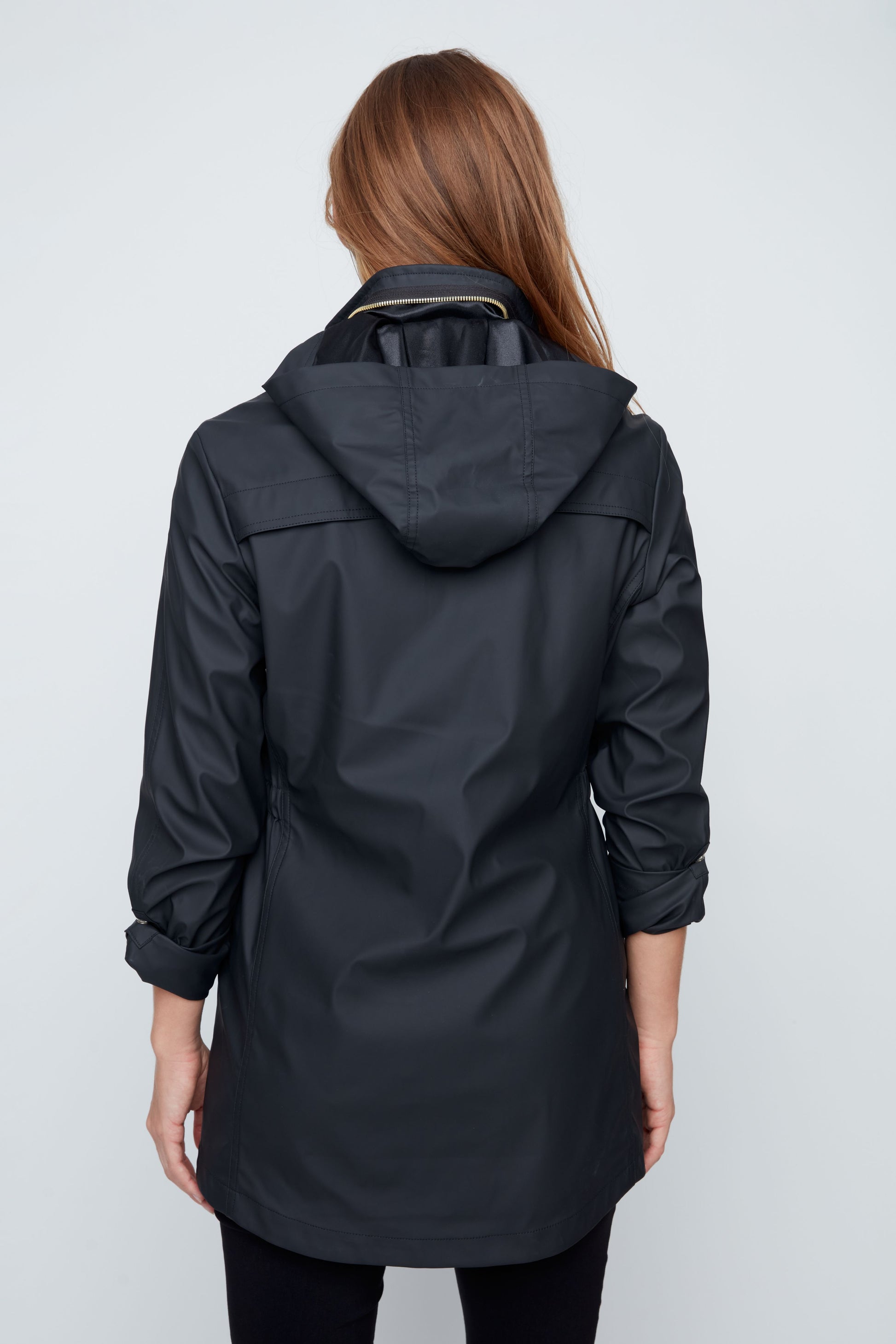 Woman wearing a black raincoat on a white background