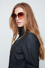 Woman wearing sunglasses and a black jacket against a light gray background