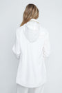 Person wearing a white oversized shirt against a plain background