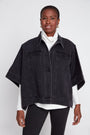 Woman wearing a black denim jacket over a white shirt on a white background