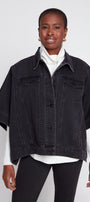 Woman wearing a black denim jacket over a white shirt on a white background