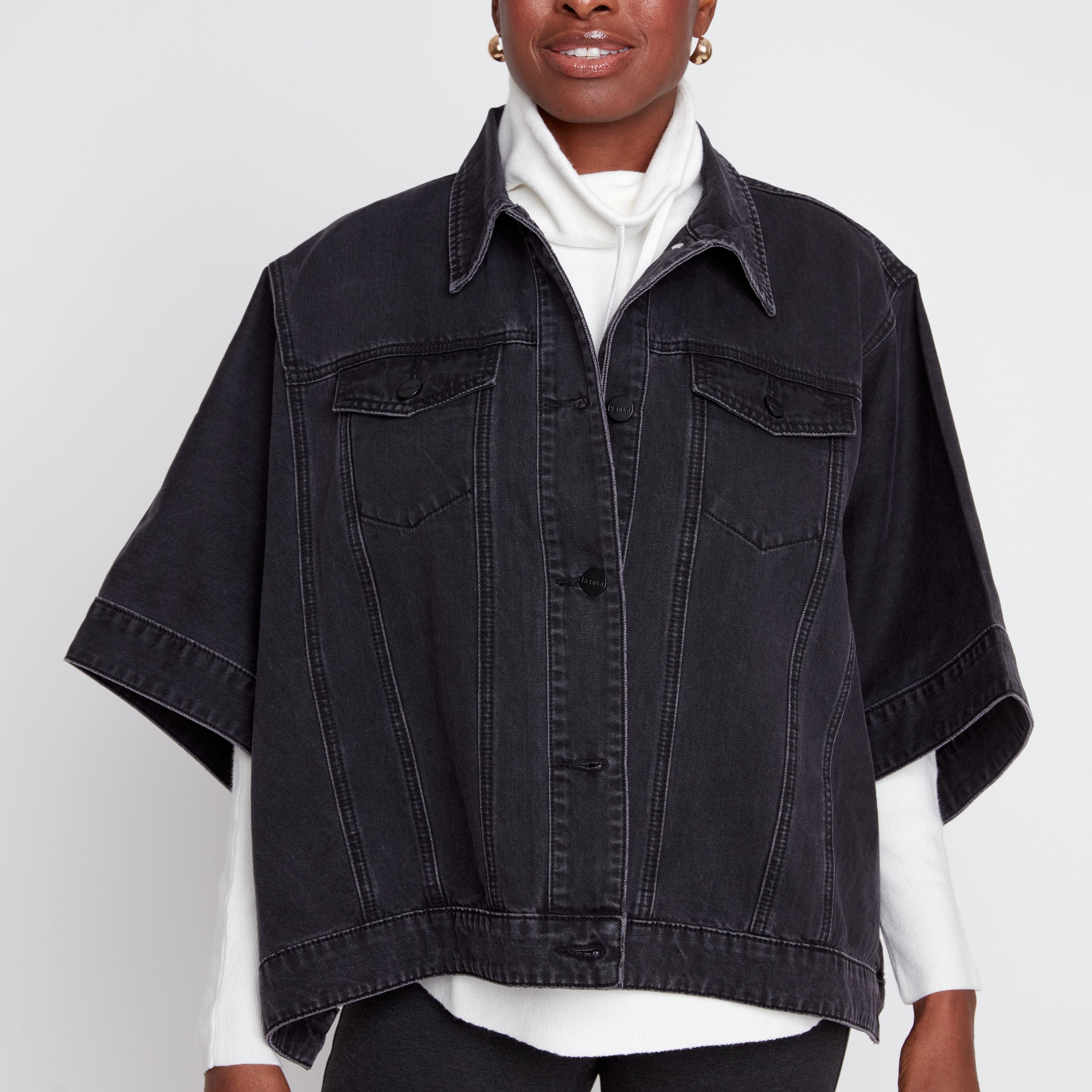 Woman wearing a black denim jacket over a white shirt on a white background