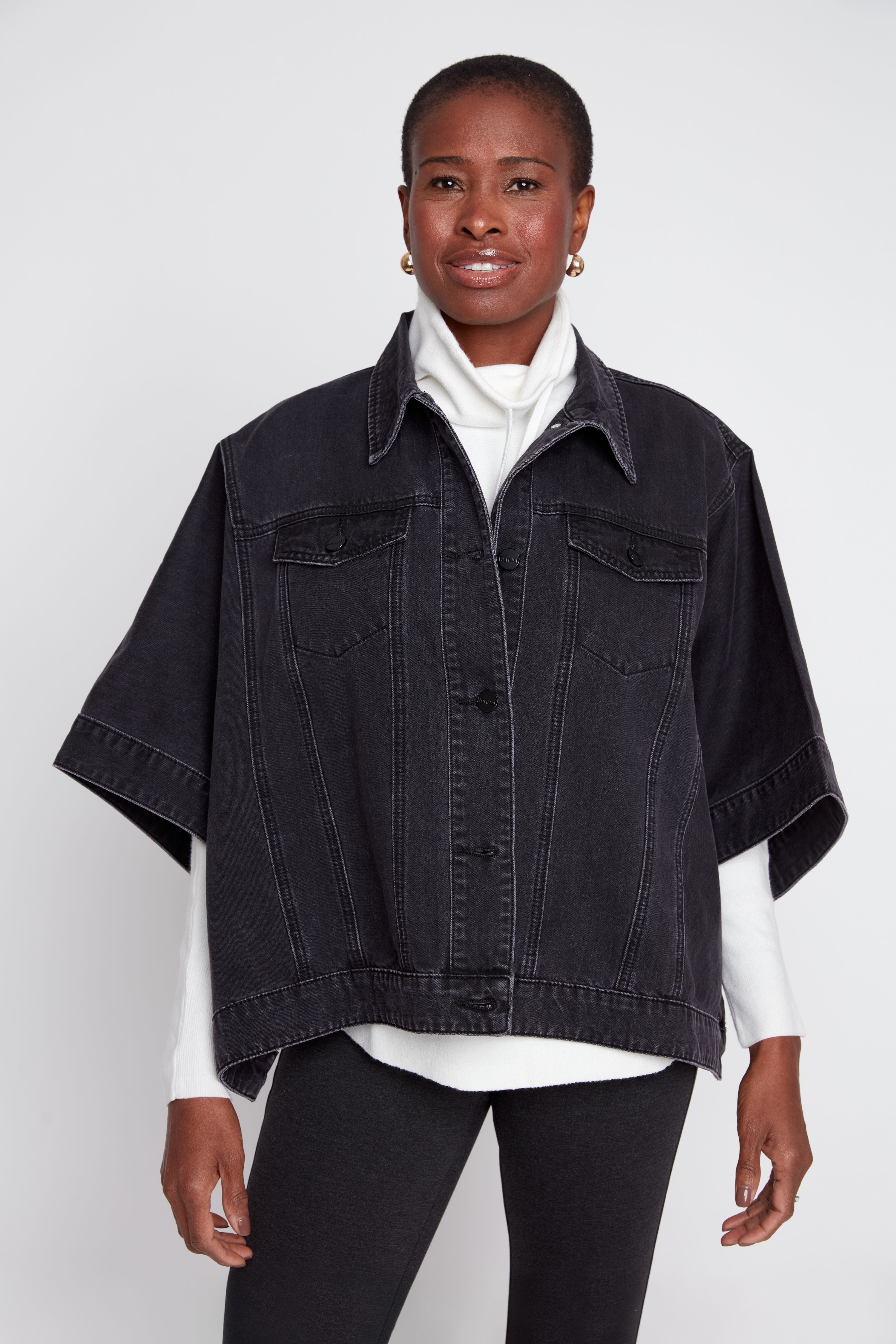 Woman wearing a black denim jacket over a white shirt on a white background