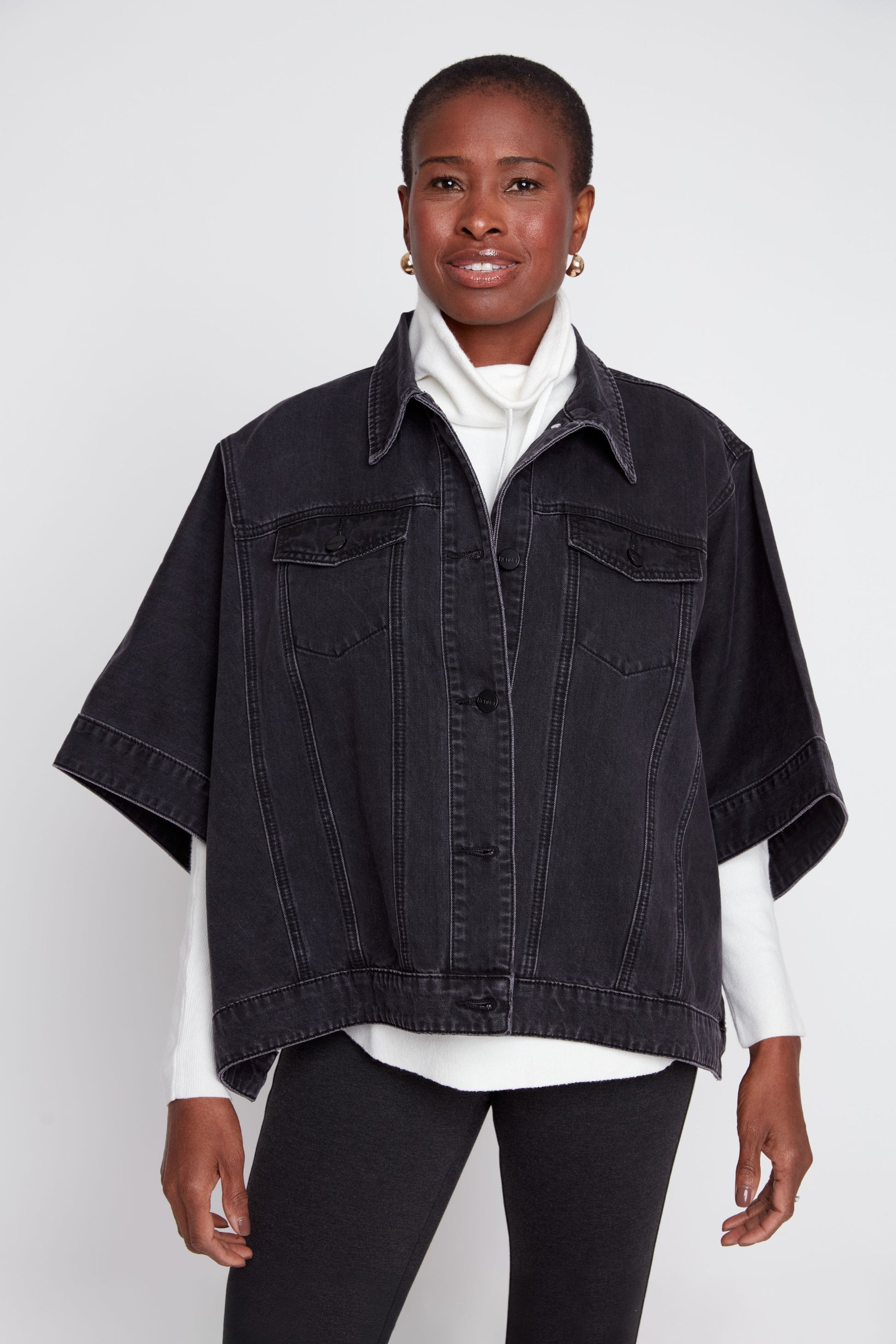 Woman wearing a black denim jacket over a white shirt on a white background