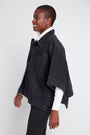 Person wearing a black denim jacket with white lining on a white background