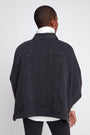 Person wearing a black denim jacket on a white background