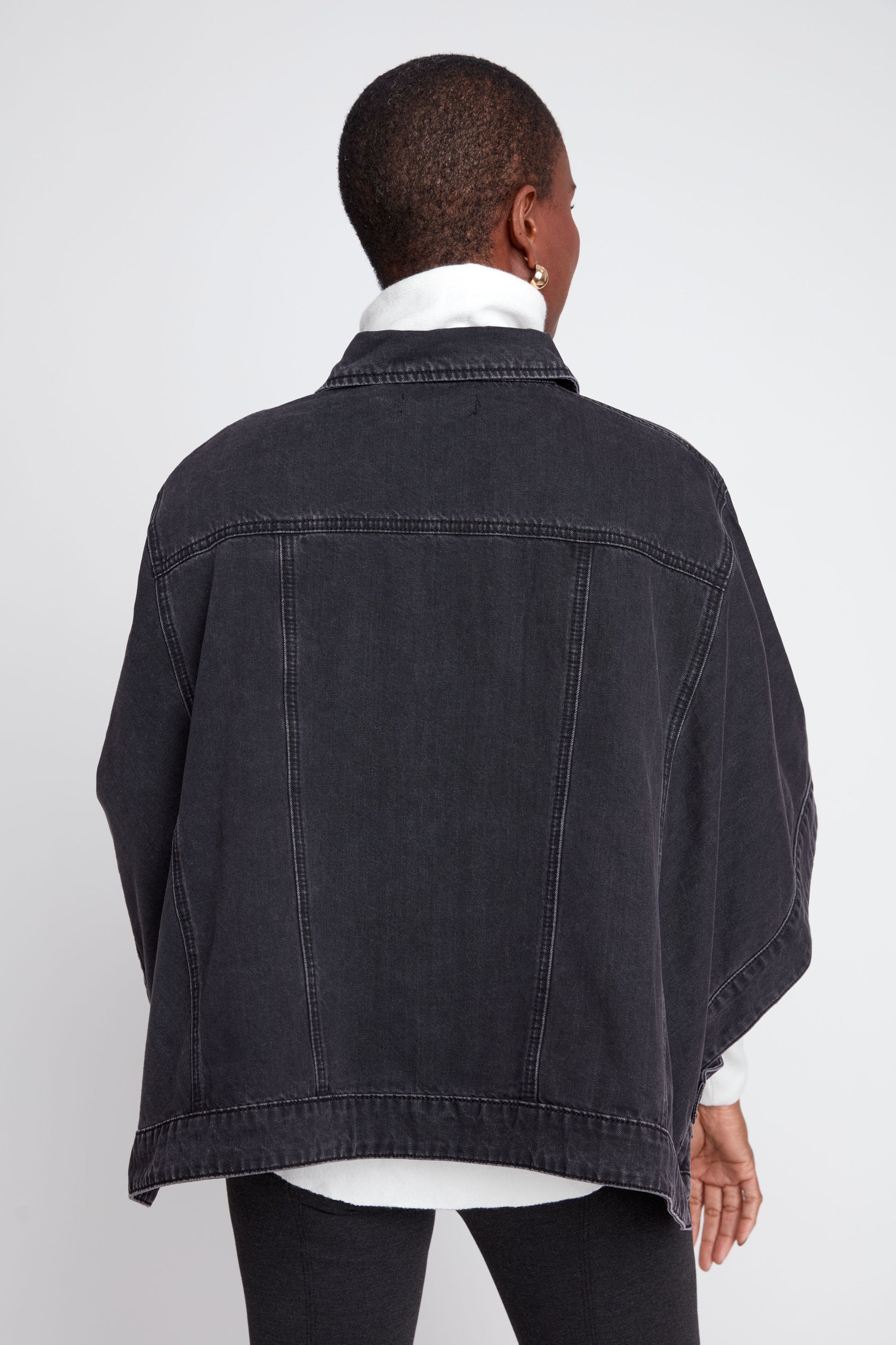 Person wearing a black denim jacket on a white background