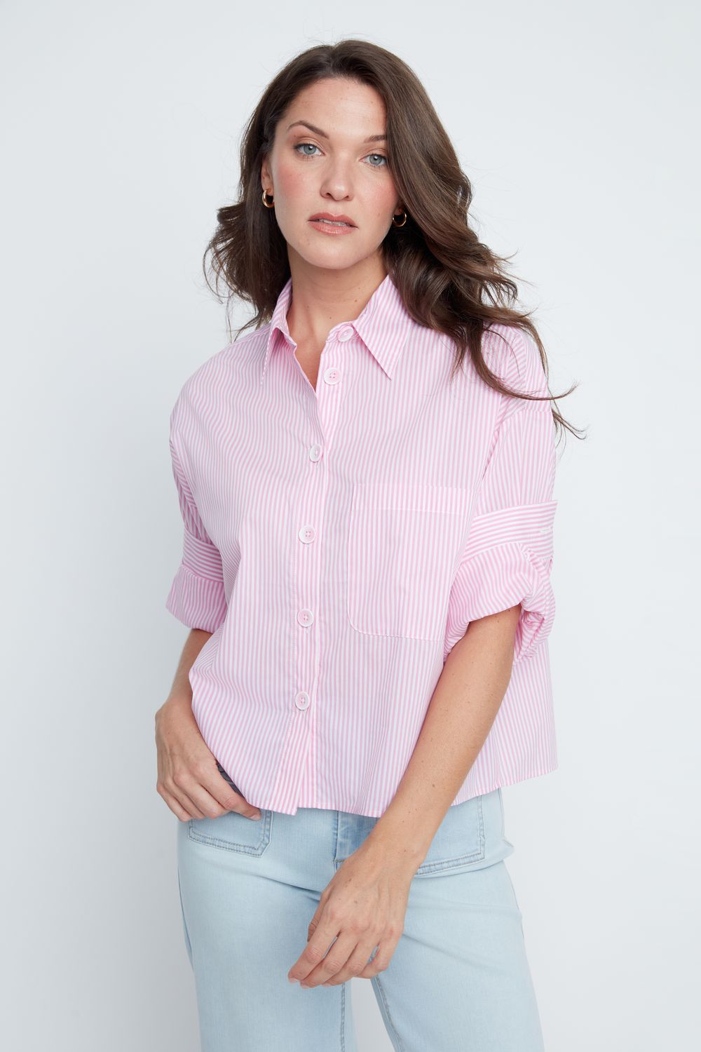 Woman wearing a pink striped shirt and light blue jeans against a white background