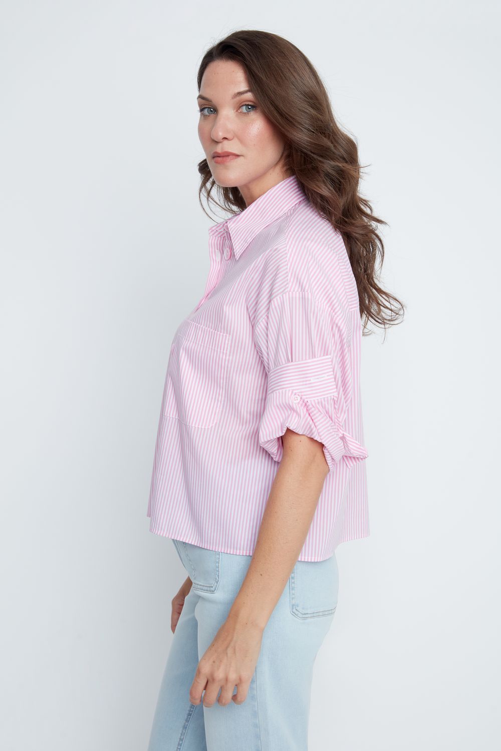 Woman wearing a light pink striped shirt and light blue jeans on a white background