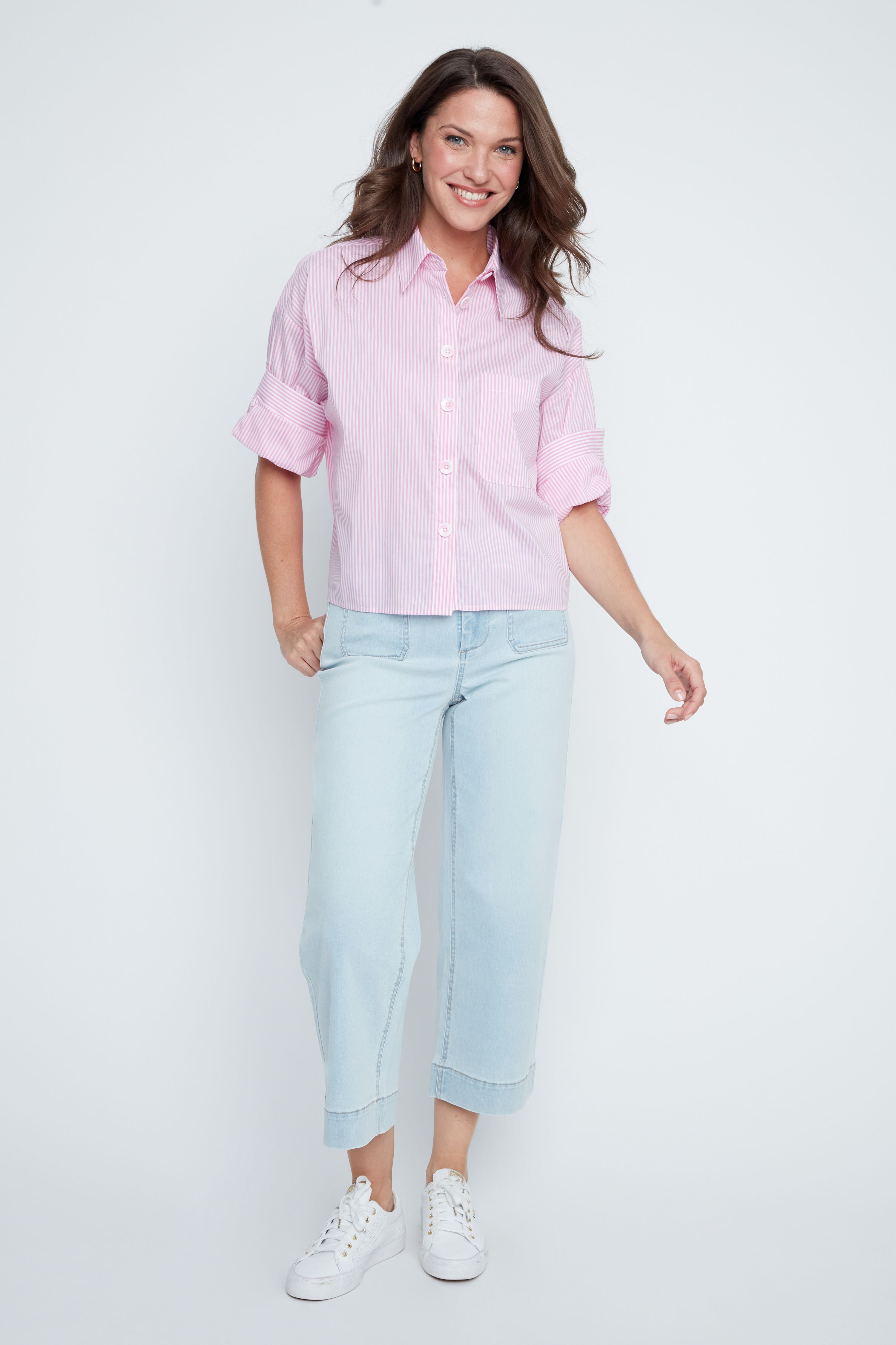 Woman wearing a light pink shirt and light blue jeans on a white background