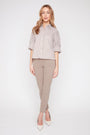 Woman wearing a striped shirt and beige pants on a white background