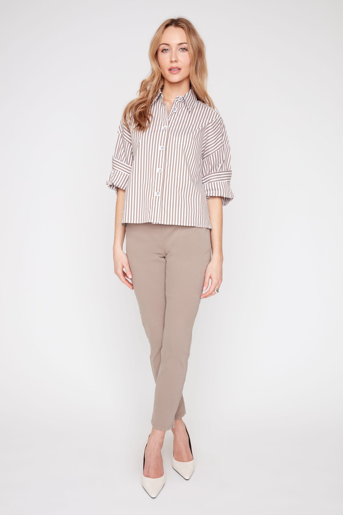 Woman wearing a striped shirt and beige pants on a white background