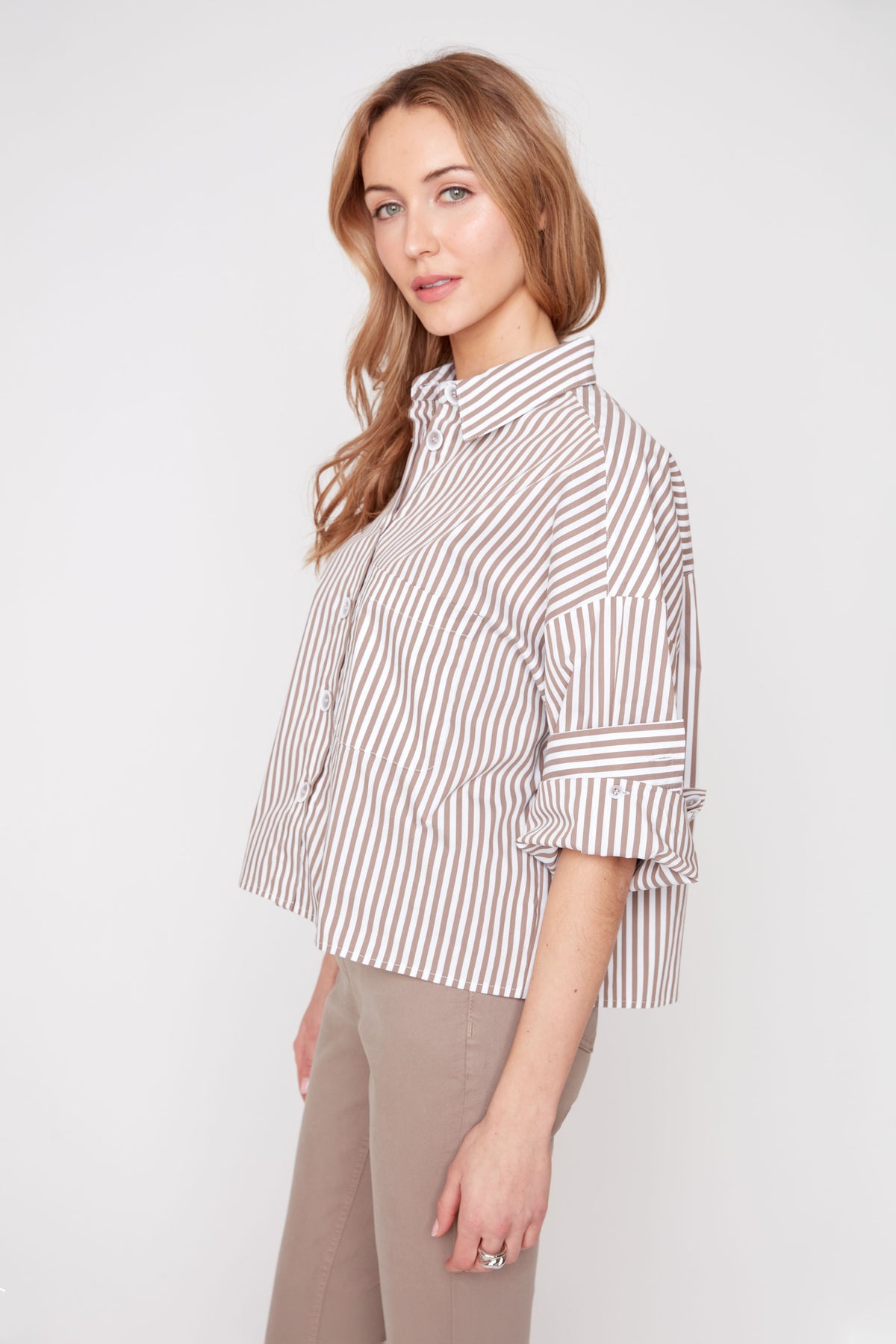 Woman wearing a striped shirt and beige pants on a white background