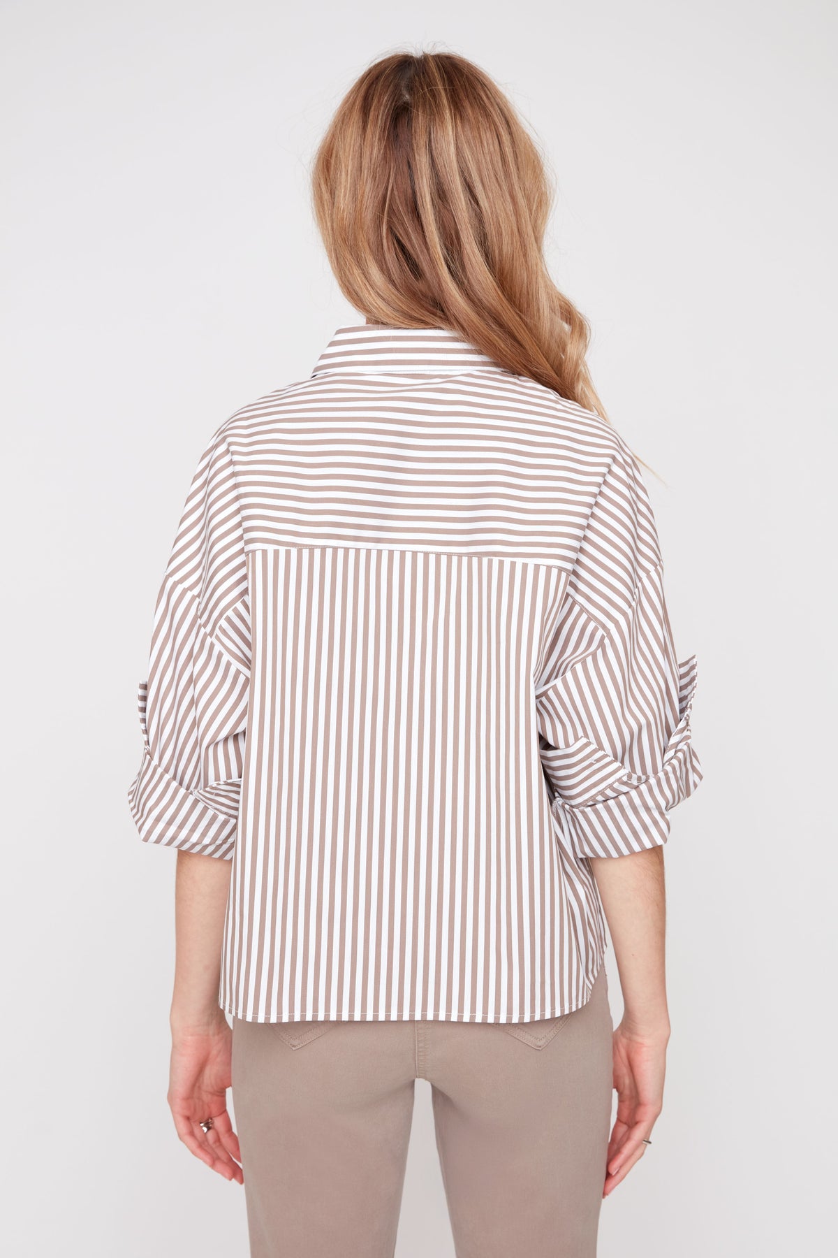 Woman wearing a striped shirt and beige pants on a white background
