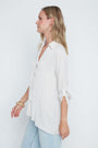 Woman wearing a white blouse and light blue pants against a white background