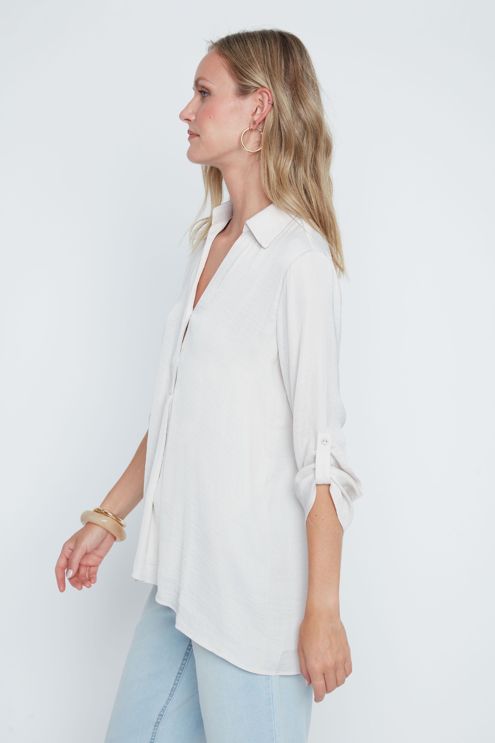 Woman wearing a white blouse and light blue pants against a white background
