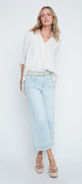 Woman wearing a white blouse and light blue pants on a white background