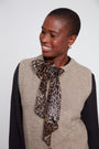 Woman wearing a leopard print scarf with a neutral background