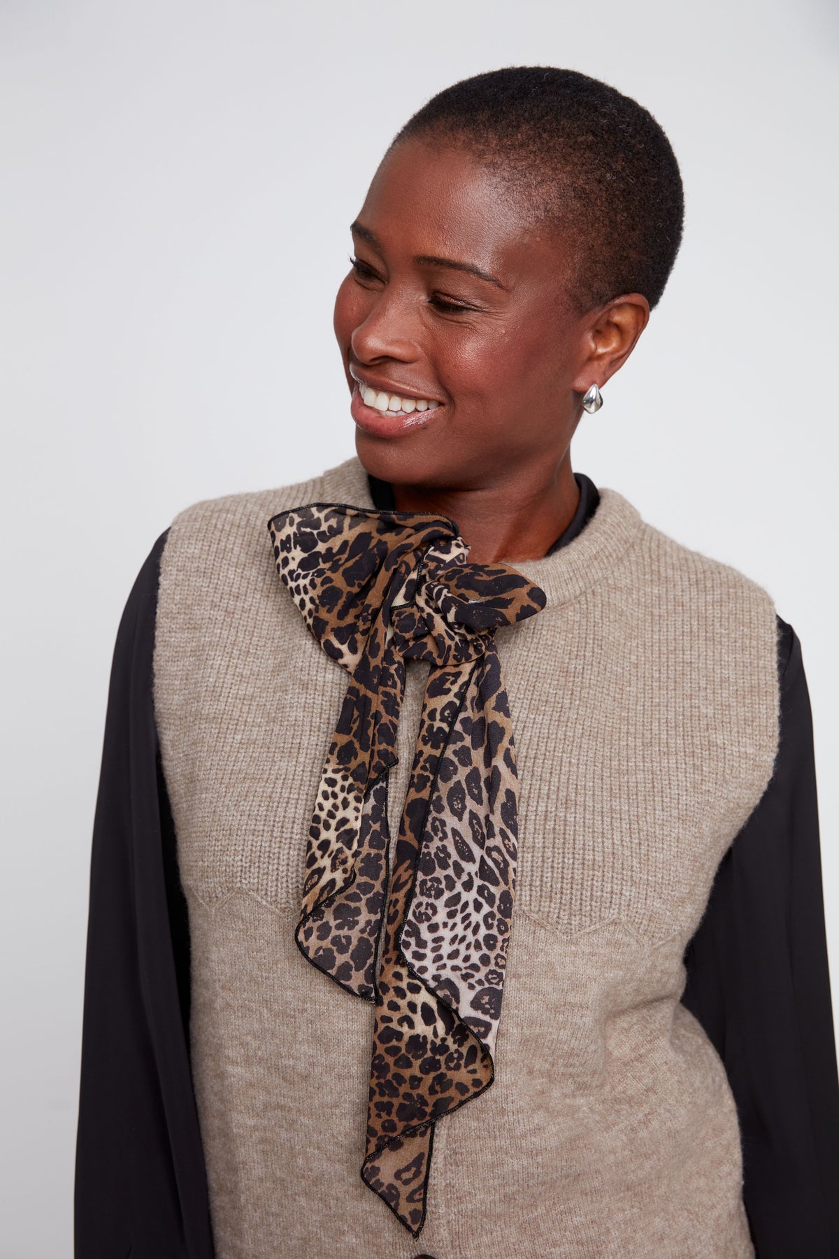 Woman wearing a leopard print scarf with a neutral background