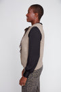 Person wearing a beige vest over a black shirt with a leopard print skirt on a white background