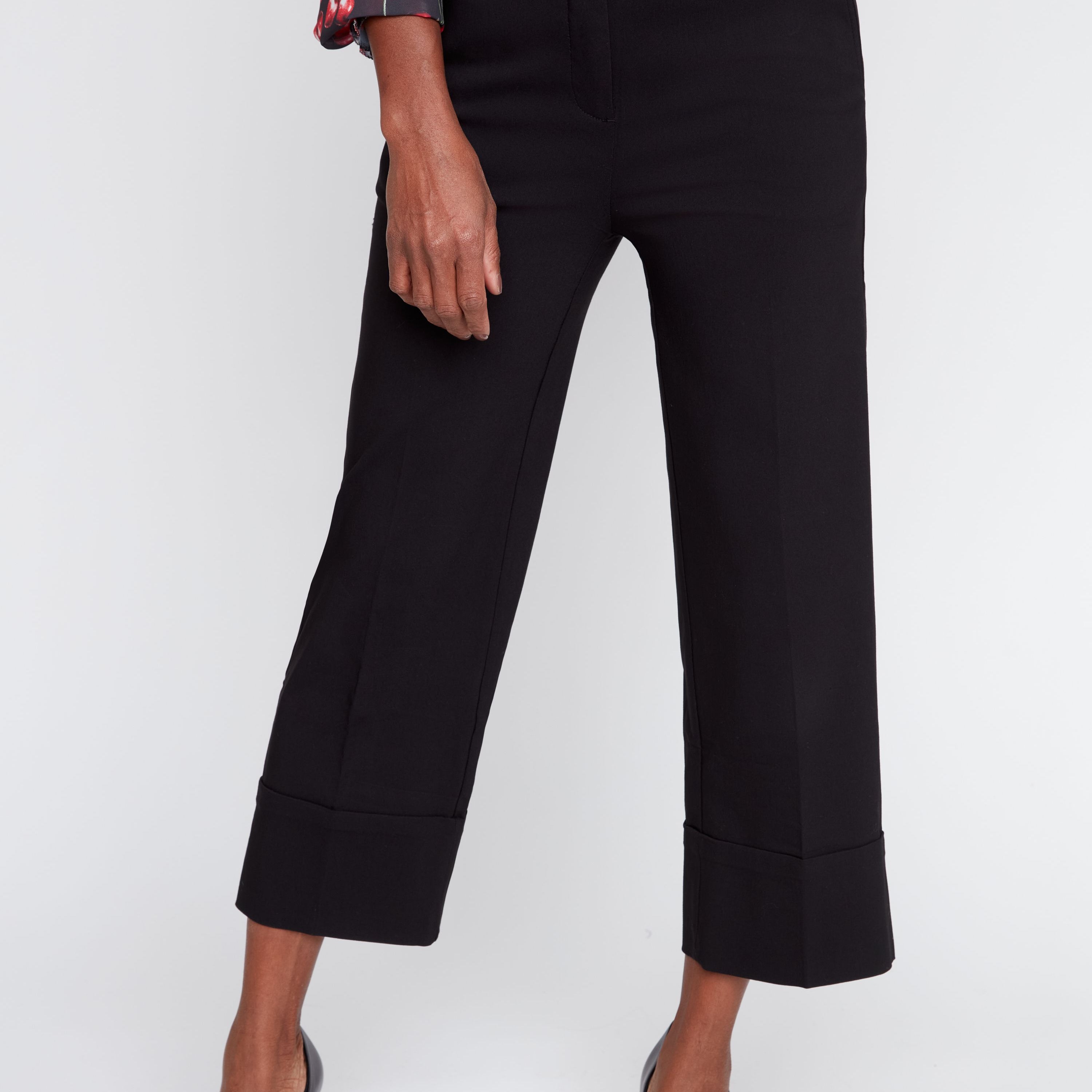 Person wearing black cropped pants with a floral blouse on a white background