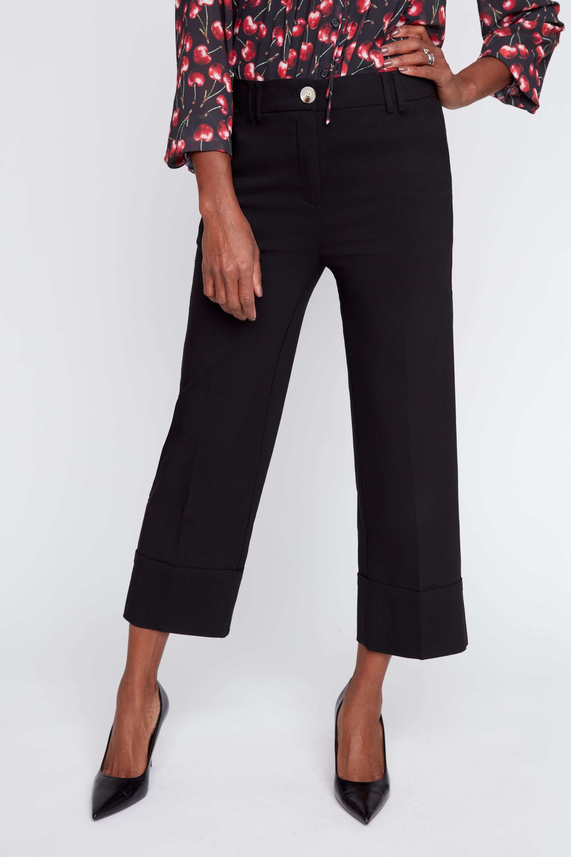 Person wearing black cropped pants with a floral blouse on a white background