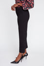 Person wearing black pants and black high heels on a white background