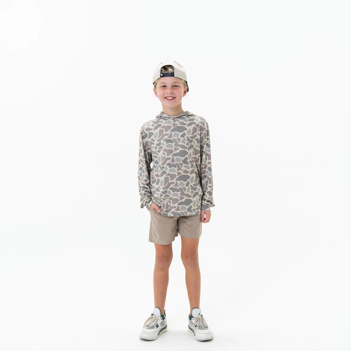 Child wearing a patterned long-sleeve shirt and beige shorts on a white background