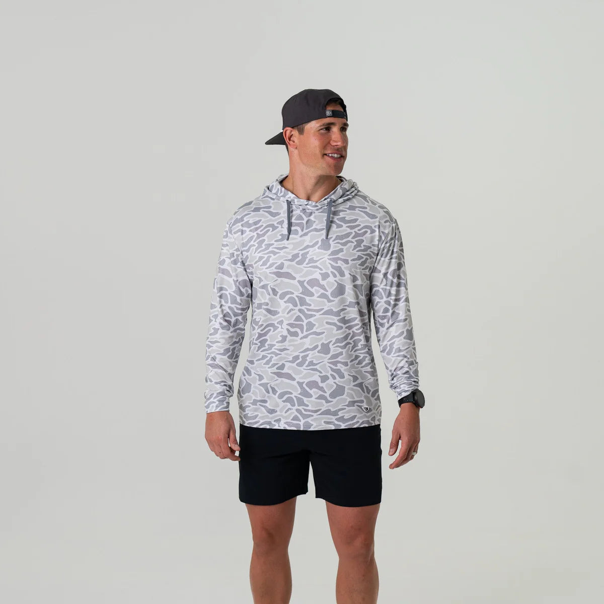 Man wearing a patterned hoodie and black shorts on a plain background