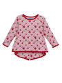 A children's long-sleeve pajama top in light pink with a repeating Santa Claus and gift print, finished with red trim on the collar, cuffs, and hem.